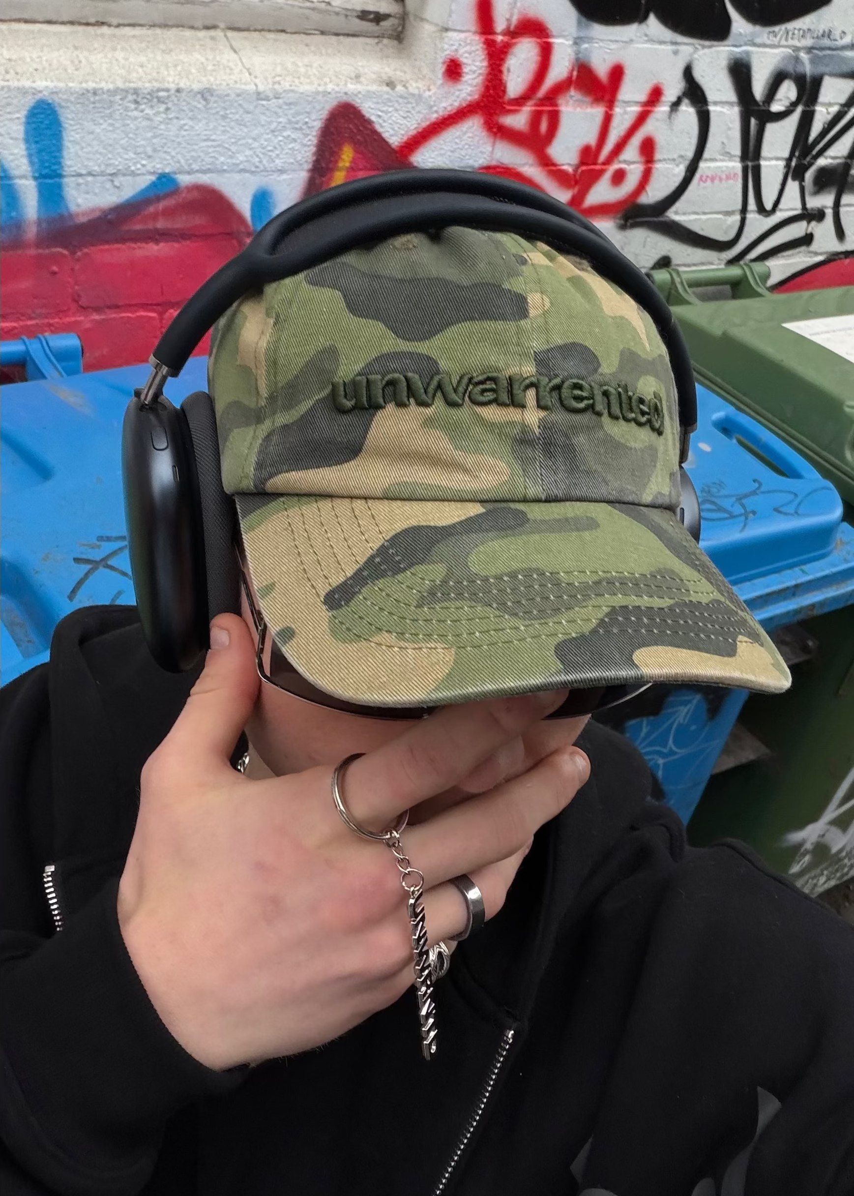 Close-up of the embroidered Unwarrented logo on the camo field cap